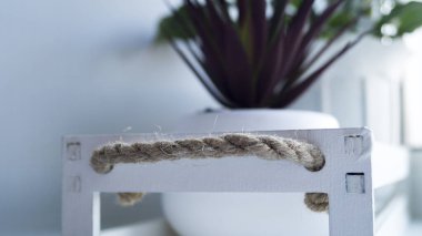 İpten yapılmış sapları olan beyaz tahta bir çiçek kutusunun parçası. Halata odaklan. İç mekan, depolama ve dekorasyon kavramı.