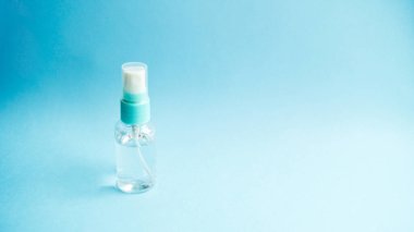 Mavi arka planda kapağı olan bir şişede sprey şeklinde antiseptik. Virüslere karşı önlem ve koruma. Sağlık ve ilaç servisi. Coronavirus. Covid - 19.