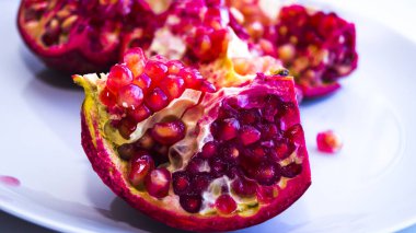 Sulu, taze, olgun bir meyve tabağında. Dilimlenmiş nar. Düzgün beslenme, taze sıkılmış meyve suyu..