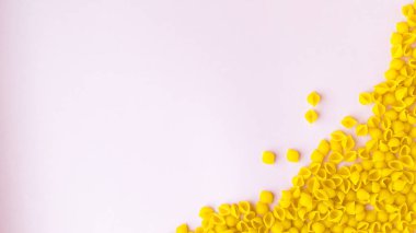 Kabuk şeklinde serpiştirilmiş makarna ve pembe arka planda katkı maddeleri..