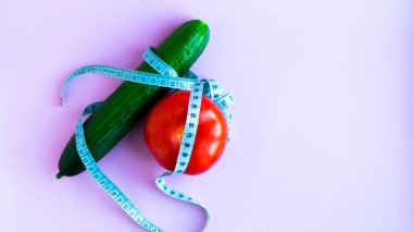 Diyet, sağlıklı beslenme, yiyecek ve kilo verme konsepti. Sebze besin. Sağlığınıza. Salatalıklı domates ve pembe bir arka planda mezura. Mesaj için yer. Uzayı kopyala Seçici odak.