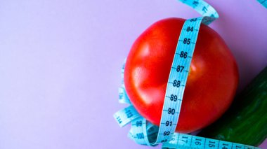 Diyet, sağlıklı beslenme, yiyecek ve kilo verme konsepti. Sebze besin. Sağlığınıza. Salatalıklı domates ve pembe bir arka planda mezura. Mesaj için yer. Uzayı kopyala Seçici odak.