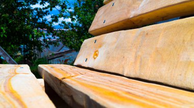 El yapımı ahşap bir bankın yan görüntüsü. Bahçe mobilyası. Tedavi edilmemiş odun. Ülkede dinlenmek. Bahçe düzenleme. Seçici odak.