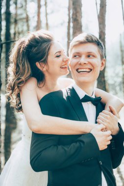 Düğün çifti, beyaz gelinlik içinde gelin ve damat ormanda yürüyor, gülüşerek gülüyorlar