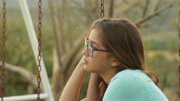 一个年轻女子在秋千里的笑脸画像 一个年轻女子在秋千里沉思 — 图库视频影像