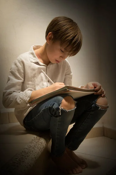 Çocuk ödevini yapıyor. Evdeki merdivenlerde ders çalışıyor.