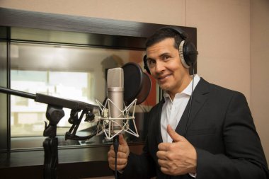 Aktör ve radyo spikeri kulaklıkları ve mikrofonuyla film kaydediyor, radyo sahnesi çekiyor ve şarkı söylüyor.