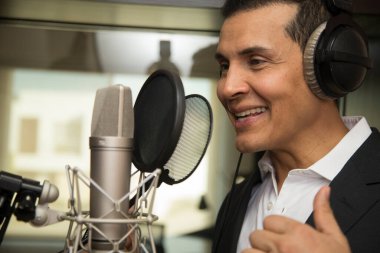 Aktör ve radyo spikeri kulaklıkları ve mikrofonuyla film kaydediyor, radyo sahnesi çekiyor ve şarkı söylüyor.