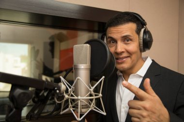 Aktör ve radyo spikeri kulaklıkları ve mikrofonuyla film kaydediyor, radyo sahnesi çekiyor ve şarkı söylüyor.