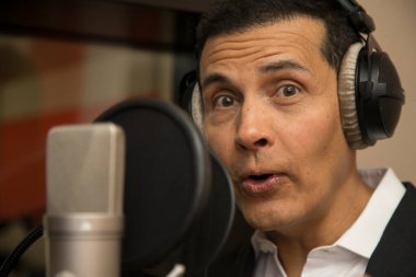 Aktör ve radyo spikeri kulaklıkları ve mikrofonuyla film kaydediyor, radyo sahnesi çekiyor ve şarkı söylüyor.