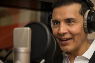 Aktör ve radyo spikeri kulaklıkları ve mikrofonuyla film kaydediyor, radyo sahnesi çekiyor ve şarkı söylüyor.