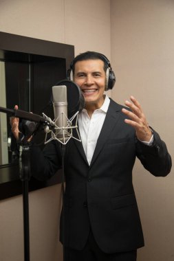 Aktör ve radyo spikeri kulaklıkları ve mikrofonuyla film kaydediyor, radyo sahnesi çekiyor ve şarkı söylüyor.