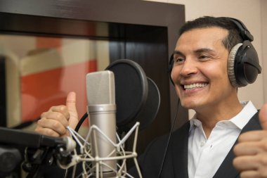 Aktör ve radyo spikeri kulaklıkları ve mikrofonuyla film kaydediyor, radyo sahnesi çekiyor ve şarkı söylüyor.