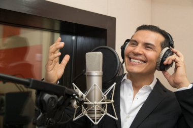 Aktör ve radyo spikeri kulaklıkları ve mikrofonuyla film kaydediyor, radyo sahnesi çekiyor ve şarkı söylüyor.