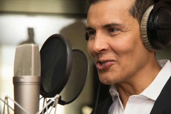 Aktör ve radyo spikeri kulaklıkları ve mikrofonuyla film kaydediyor, radyo sahnesi çekiyor ve şarkı söylüyor.