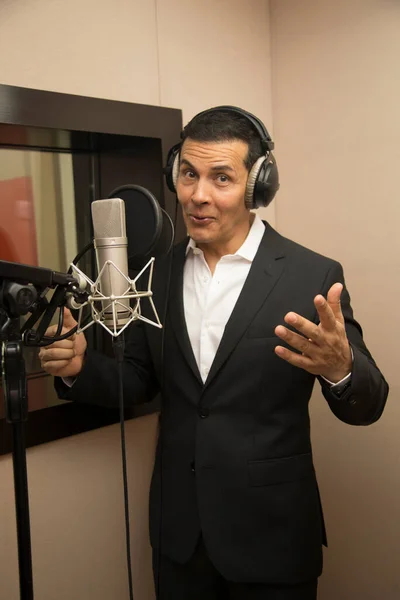 Aktör ve radyo spikeri kulaklıkları ve mikrofonuyla film kaydediyor, radyo sahnesi çekiyor ve şarkı söylüyor.