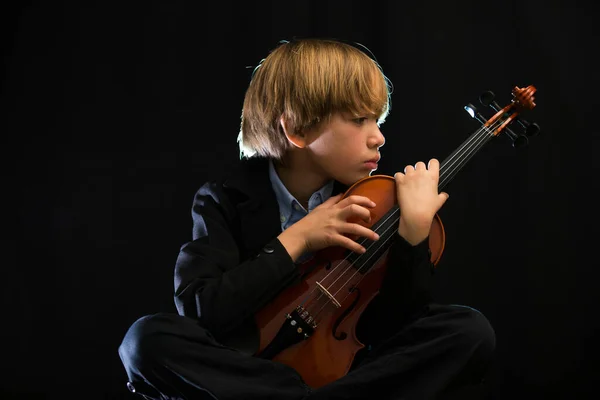 バイオリンを抱きかかえて音楽への愛の態度で男の子はカメラに自分のバイオリンを示す — ストック写真