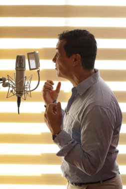 Radyo spikeri ve mikrofonla profesyonel stüdyoda dublaj yapıyor.