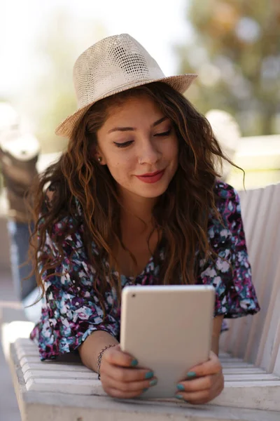 Teknoloji kullanan güzel kız, şapkalı ve gözlüklü Latin kız ipad 'ine danışıyor. 