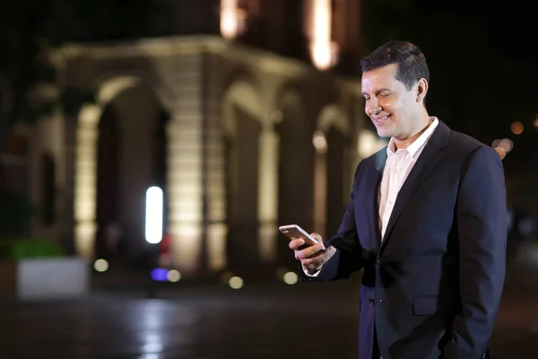 Sokakta cep telefonu olan yakışıklı bir iş adamı yakışıklı bir Latin yönetici ofisten çıkıyor telefonda konuşuyor ve Casimir takım elbise giyiyor.