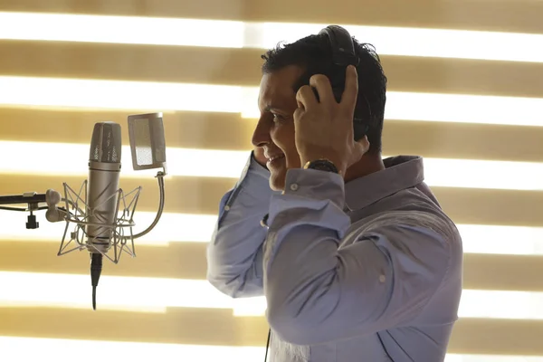 Radyo spikeri ve mikrofonla profesyonel stüdyoda dublaj yapıyor.