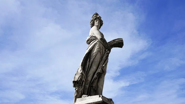 Roma 'daki gri kadın heykeli mavi arka planda ve arkasında bulutlar var..
