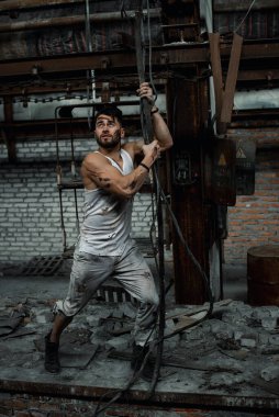 Fabrikada çalışan işçi, elektrik döşeyen, yırtık iş şekli, spor figürü.