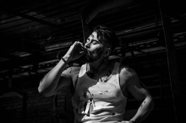 Moladaki adam sigara içiyor, sakallı ve spor figürlü.