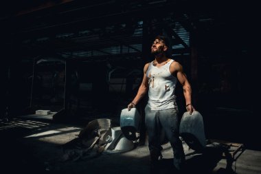 Işık altındaki adam seramik tankı iki elle tutuyor, sporcu adam, metin için yer var.