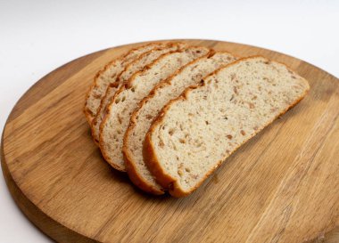 Birkaç parça doğranmış kepek ekmeği dokulu bir tahtanın üzerinde duruyor.