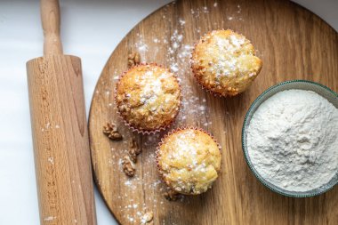 Lezzetli, sadece ahşap bir tahtanın üzerinde pişmiş kekler var. Un her yere saçılmış, cevizler yalan söylüyor. Yakınlarda ahşap bir raptiye yatıyor.