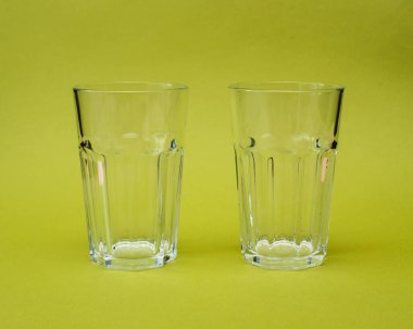 Açık yeşil arka planda iki cam bardak.