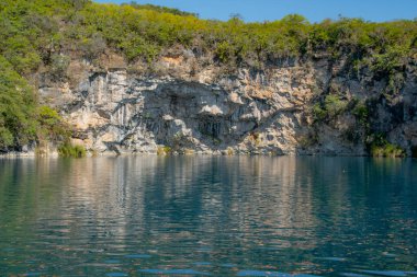 Candelaria Cenote of Huehuetenango, Guatemala, güneşli bir günde suyun turkuaz rengini ve sudaki ağaçların yansımasını görebilirsiniz..