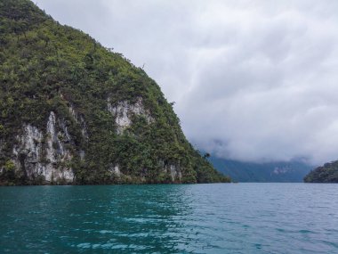 Guatemala, Huehuetenango 'daki Laguna Brava manzarası bulutlu bir günde ama yine de suyun mavi rengini ve yeşil dağlarını görebilirsiniz..