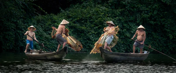 Высококачественное фото четырех вьетнамских рыбаков, плавающих на лодках, ловящих рыбу в рыболовных сетях — стоковое фото