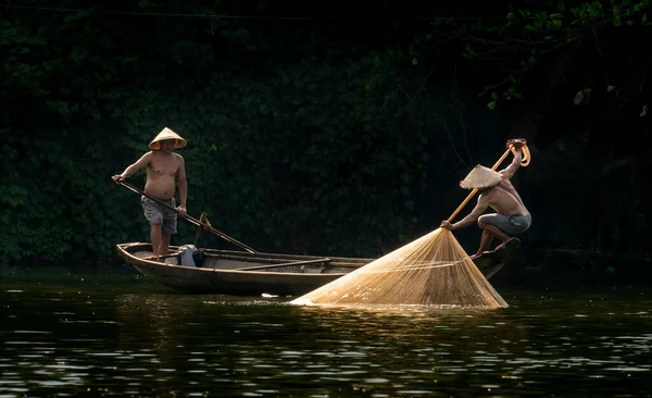 Um tiro cativante de dois pescadores vietnamitas arrastando uma rede de pesca no rio — Fotografia de Stock