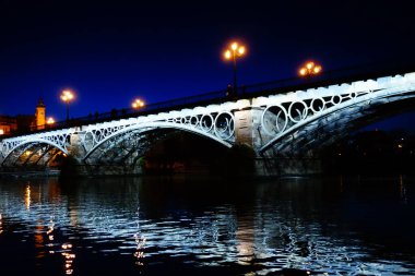 Seville 'deki Triana Köprüsü, Guadalquivir nehri ile, gün batımında.