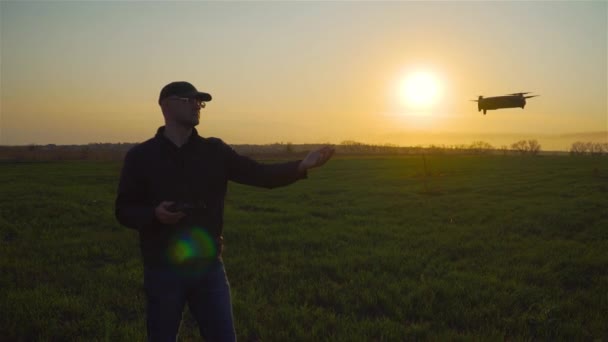 Petit drone volant près de jeune homme caucasien en verre avec la main tendue au coucher du soleil — Video