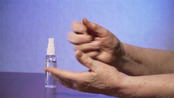 Karantina sırasında sıvı sprey el dezenfektanı kullanan yaşlı kadın ellerini temizlemek ve derisini virüs ve mikroplara karşı temizlemek için alkol jeli kullanıyor. — Stok video