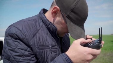 Kapaklı çiftçi uzaktan kumandayı tutuyor ve tarlalarda uçan kuadrokopter monitörüne bakın.