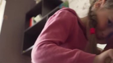 Küçük kız eğleniyor ve sallanan sandalyede gülüyor. Oyuncak geyik, çocuk odasında tatlı bir kız için.
