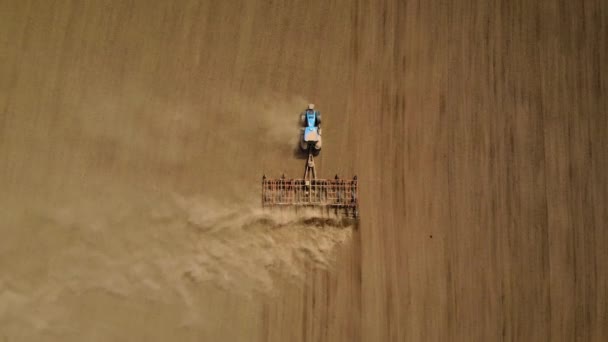Верхний вид с воздуха голубой трактор пашет сельскохозяйственные почвы в поле для посева сельскохозяйственных культур — стоковое видео