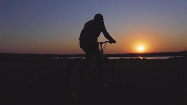 Boy kid ridning cykel på våren nära floden vid vacker solnedgång i slow motion — Stockvideo