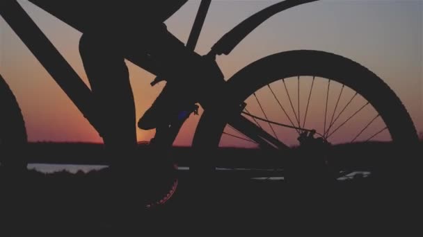Cinematic retro style shot cyclist rides mountain bike at evening in rays of sunset in close up — Stock Video