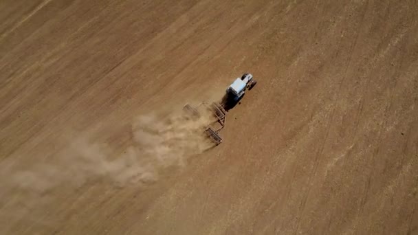 ディスクの矢印を持つブルートラクターは、乾燥したフィールドのほこりだらけの地面を耕す — ストック動画