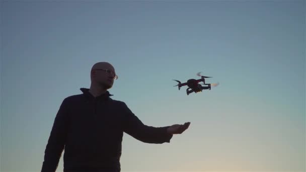 Felnőtt férfi szemüvegben távirányító képernyővel repülő drón alatt napkelte este — Stock videók