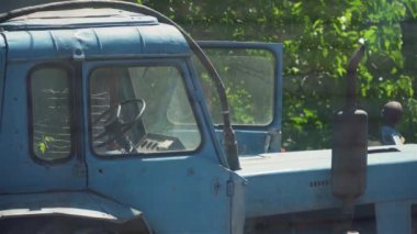 Traktör evin bahçesinde ve egzoz borusundan duman çıkıyor.