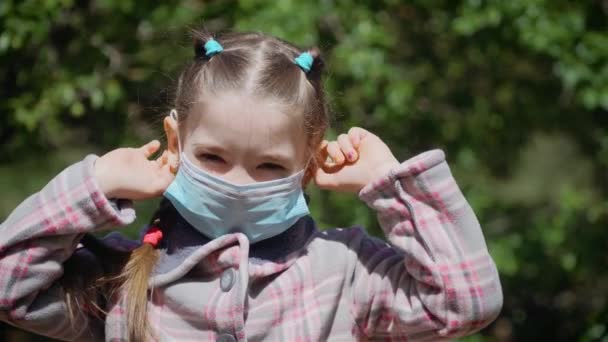 Niña se quita la máscara médica y respira profundamente y sonriendo mirando a la cámara — Vídeos de Stock