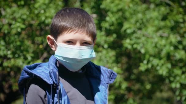 Retrato de niño lindo se quita la máscara médica. El niño respira profundamente y sonríe mirando a la cámara — Vídeos de Stock