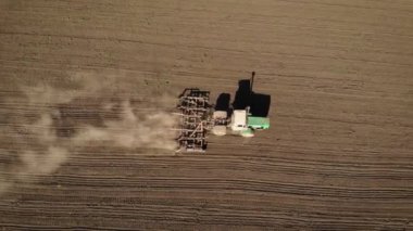 Güçlü traktördeki çiftçi sabanla tarlaya tahıl ekmeye hazırlanıyor.